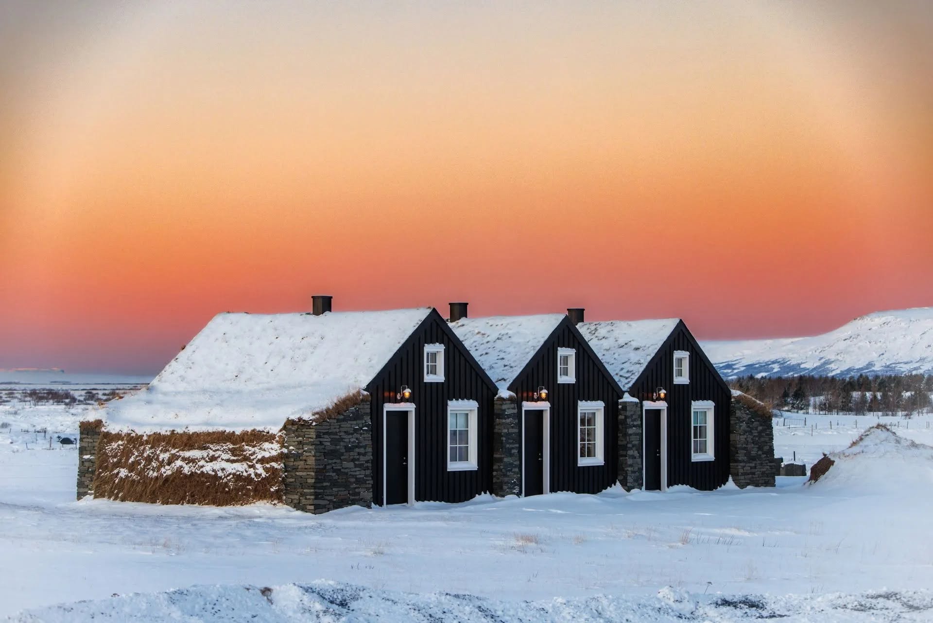 Turf-roofed cottages at Torfhús Retreat on the Golden Circle under a pink winter sky