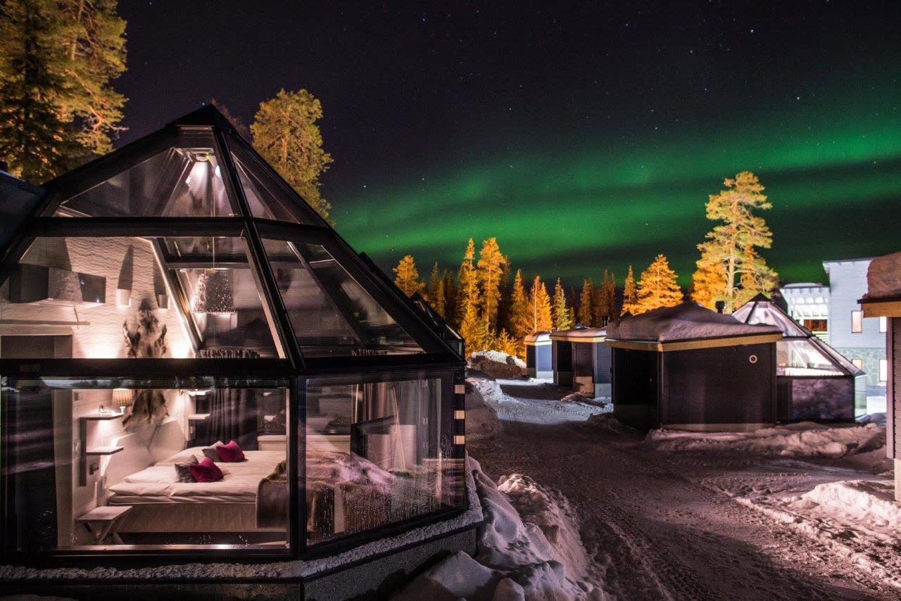 Glass-roofed aurora igloos at Santa's Hotel Aurora & Igloos in Luosto beneath a green aurora sky at night